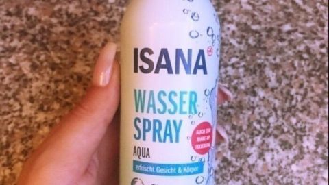 Ein Hand hält eine ISANA Wasser Spray Dose, ideal zum Abkühlen und gut einschlafen trotz Hitze, vor einem Steinboden.