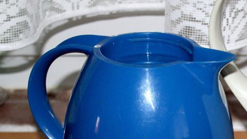 Kaffeemaschinenreiniger kann auch für braune Verfärbungen an der Thermoskanne verwendet werden. Eine blaue Thermoskanne steht auf einem Tisch und ist bereit, mit Kaffeemaschinenreiniger gereinigt zu werden.
