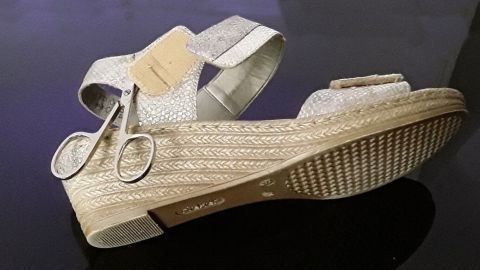 Ein eleganter Schuh mit Klettverschluss liegt auf einem glänzenden Tisch, umgeben von einem modernen, schlichten Raum.