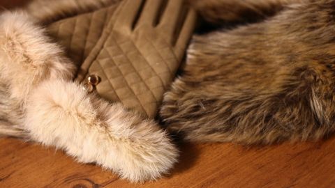 Ein Pelzmuff liegt auf einem rustikalen Holztisch, neben einem Paar handschuhähnlicher Accessoires, um Gerüche zu entfernen.