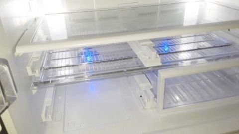 Transparente Kühlschrankregale sind ordentlich angeordnet, während bläuliches Licht den inneren Raum beleuchtet.
