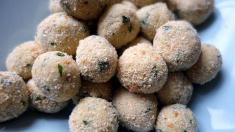Kleine, runde Hirse-Kartoffel-Bällchen sind appetitlich angerichtet auf einem weißen Teller, bereit zum Genießen.