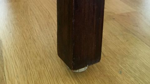 Ein Stuhlbeine mit einer Korkunterlage steht auf einem Holzboden, um Kratzer zu vermeiden und den Boden zu schützen.