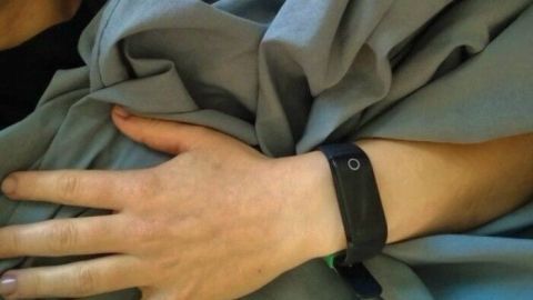 Eine Hand liegt entspannt unter einer blauen Decke, während der Körper in einer ruhigen Schlafposition auf einem Bett liegt.