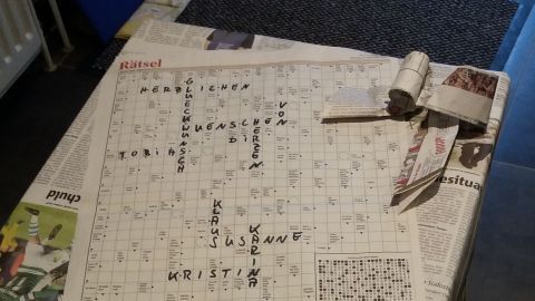 Ein Geschenk ist mit Zeitungen und einem Bienenwachstuch eingepackt und liegt auf einem Fliesenboden.