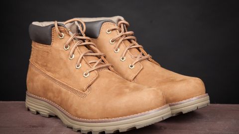 Braune Schuhe stehen auf einer Oberfläche, bereit, Schneeränder entfernt zu werden, im neutralen Hintergrund.