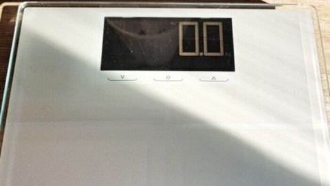 Eine digitale Waage liegt auf einem Holzfußboden, bereit zum Wiegen im Rahmen einer 1000-Kalorien-Diät.