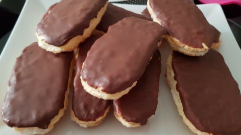 Auf einem weißen Teller liegen mehrere Teezungen aus Blätterteig, schön mit Schokolade überzogen, appetitlich angerichtet.