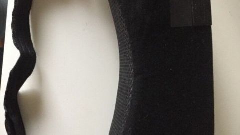 Ein schwarzes, gepolstertes Kissen mit Tragegurt liegt auf einem Tisch, ideal für Rücken- und Bauchschläfer.