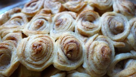 Ein kunstvoll dekorierter Apfelkuchen mit spiralförmigen Teigrollen wird appetitlich präsentiert.