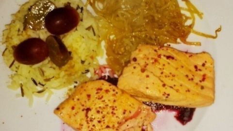 Zarte, pochierte Lachsstücke liegen auf Rote-Bete-Sauce, begleitet von Mungosprossen und aromatischem Reis.