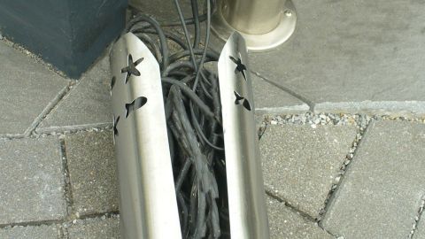 Ein WC-Rollenhalter beherbergt Kabel, die ordentlich verstaut und vor Sicht geschützt sind, auf einem Boden aus Pflastersteinen.