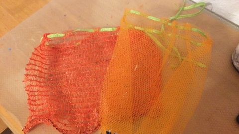 Zwei wiederverwendete Netze für Zwiebeln und Kartoffeln liegen auf einem Tisch, ideal zum Plastikverzicht.