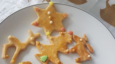 Kekse in verschiedenen Formen liegen auf einem Teller, bunt verziert mit Zuckerstreuseln, in festlicher Umgebung.