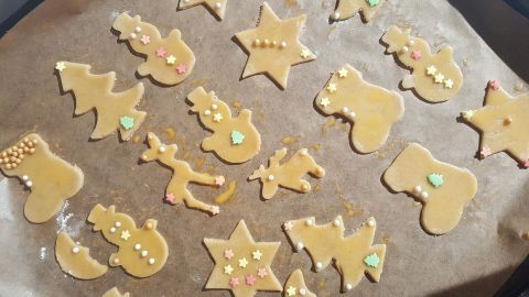 Bunte Ausstecherle mit Zimt liegen auf ein Blech, bereit zum Backen in der weihnachtlichen Küche, um Freude zu bringen.