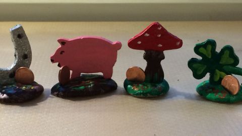 Ein Glücksbringer aus vier farbenfrohen Figuren: ein Hufeisen, ein Schwein, ein Pilz und ein Kleeblatt, alle handgefertigt.
