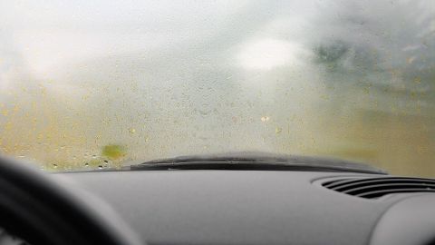 Ein Auto mit beschlagenen Scheiben steht, während die Sicht durch die Feuchtigkeit stark eingeschränkt ist.