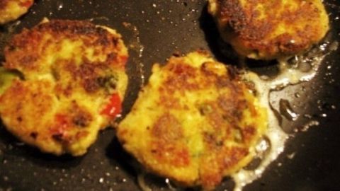 In einer Pfanne braten goldbraune Gemüse-Bratlinge, während sie in heißem Öl köcheln und knusprig werden.