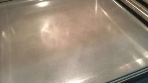 Ein glänzendes Backblech liegt in einem Backofen, bereit zur Reinigung von eingebrannten Flecken mit einfachen Mitteln.