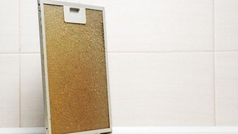 Ein Fettfilter steht aufrecht in einer modernen Küche und zeigt Verschmutzungen, die auf eine dringend notwendige Reinigung hinweisen.