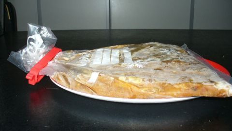 Eine gefrorene Suppe in einem Plastikbeutel liegt flach auf einem Teller, bereit zum Einfrieren in der Küche.