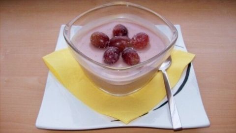 Ein Pudding mit Rotwein ist in einer Schüssel angerichtet, dekoriert mit Trauben, auf einem Teller mit Serviette.