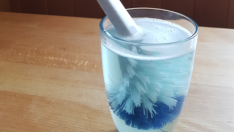 Eine Spülbürste steht in einem Glas mit Wasser und Reinigungsmittel, um effektiv Plastikmüll zu vermindern.