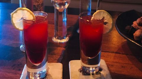 Zwei Gläser mit schwedischem Winter Drink stehen auf einem Tisch, umgeben von Kerzenlicht und einer gemütlichen Wohnzimmeratmosphäre.