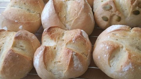 Frisch gebackene Weizenbrötchen liegen auf einem Kuchengitter, leicht goldbraun und knusprig, bereit zum Servieren.