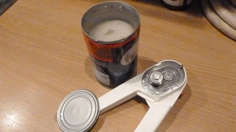 Eine Kokosmilchdose steht auf einem Tisch neben einem Dosenöffner, bereit zum stressfreien Öffnen und Entleeren.
