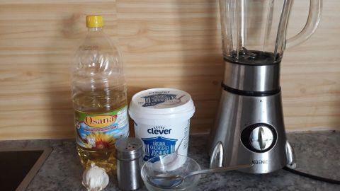 Ein Mixer steht neben einer Flasche Öl und einem Behälter mit Joghurt, bereit zur einfachen Herstellung von Knoblauchmayonnaise.