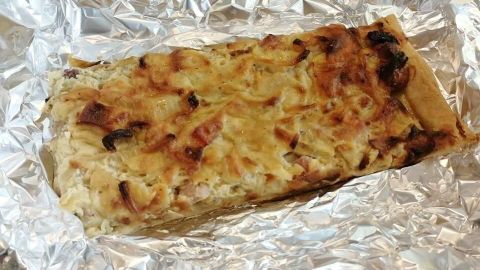 Ein Zwiebelkuchen ist auf einem Silberpapier platziert, leicht goldbraun gebacken und bereit zum Servieren.