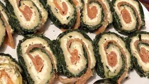 Schmackhafte Lachsrolle mit Spinat und Frischkäse auf einem Teller, in appetitliche Stücke geschnitten, wird serviert.