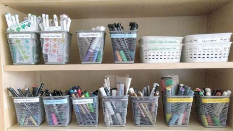 Schlichte Kunststoffbehälter auf einem Regal lagern verschiedene Stifte und Marker ordentlich und übersichtlich.