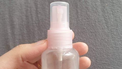 Ein handliches Sprayglas wird gehalten, bereit für die Anwendung von Teebaumöl-Spray zur natürlichen Pflege.