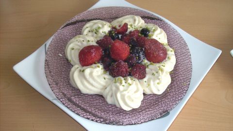 Ein cremiger Mandelcreme-Pudding ist dekorativ angerichtet und mit frischen Waldfrüchten, wie Himbeeren und Blaubeeren, garniert.