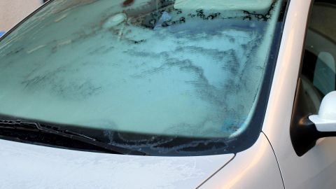 Mit Salz gegen Eis: Gefrorene Autoscheiben lassen sich schnell und effektiv mit einer Salzlösung abtauen. Einfach ein Tuch in Salzwasser tränken und vorsichtig über die vereiste Scheibe wischen, um rasch für klare Sicht zu sorgen. Eine zugefrorene Autoscheibe mit Eiskristallen auf einem weißen Fahrzeug an einem kalten Wintermorgen.