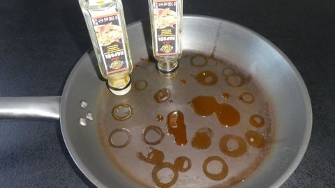 Eine Pfanne enthält gebrauchten Speiseöl, während zwei fast leere Flaschen in ihr stehen und das Öl sammeln.