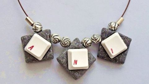 Kette mit Tastaturbuchstaben „A“, „N“ und „I“ aus grauen Elementen, schick für kreative Ausdrucksformen.