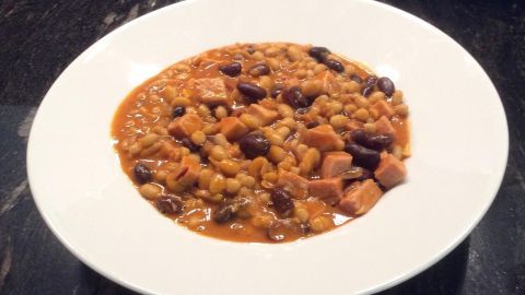 Eine Schale Bohnen-Gulasch mit weißen Bohnen und roten Bohnen, appetitlich präsentiert auf einem weißen Teller.