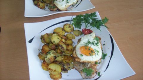 Zwei Teller mit Holzfäller-Steaks, jeweils mit Spiegelei und derbe gebratenen Kartoffeln, frisch auf einem Tisch angerichtet.