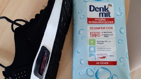Schwarzer Sneaker liegt neben einer Packung Reinigungstücher von Denk mit. Ideal zum Reinigen weißer Flächen auf Schuhen.