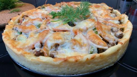 Ein gebackener Kartoffelkuchen mit Hackfleisch und TK-Gemüse, garniert mit frischem Dill, auf einer schwarzen Kochplatte.