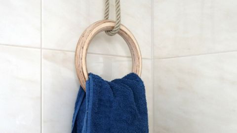 Ein Holzring hängt an einem Seil an der Wand, während ein blaues Handtuch daran hängt und das Badezimmer dekoriert.