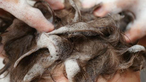 Weiche Schaumstoffe werden in lockige Haare einmassiert, um Haarsprayreste effektiv zu entfernen.