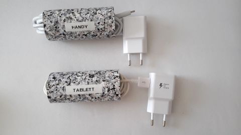Zwei Ladekabel sind ordentlich verstaut in hübschen Hüllen, verbunden mit weißen Netzteilen auf einem hellen Untergrund.