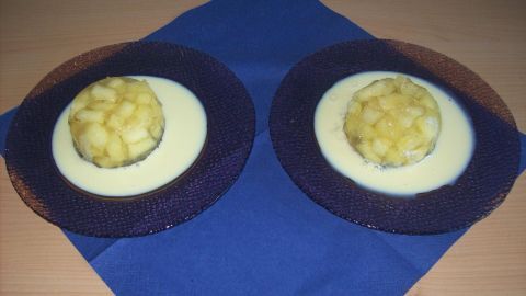 Zwei Schalen mit Apfelwürfeln in Apfelsaft-Gelee liegen auf einem blauen Tischtuch, umgeben von dekorativen Tellern.