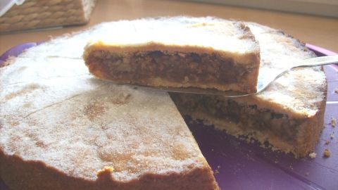 Eine saftige Baumnuss-Torte liegt auf einem Teller, mit einem Stück herausgeschnitten, hell beleuchtet am Fenster.