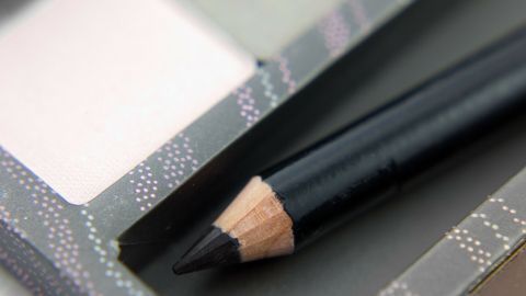 Ein schwarzer Kajalstift liegt in einem Kosmetikbehälter und zeigt die spitz zulaufende, angespitzte Mine.