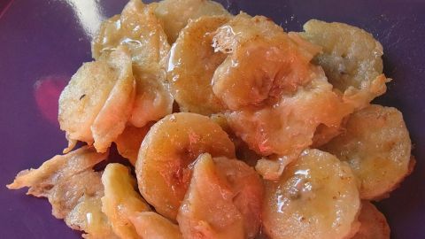 Gebackene Bananen liegen goldbraun auf einem lila Teller und verlangen nach einem köstlichen Genusserlebnis.